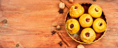 Photo for Tasty baked autumn apples with nuts and raisins on a wooden rustic table. Space for text, long banner. - Royalty Free Image