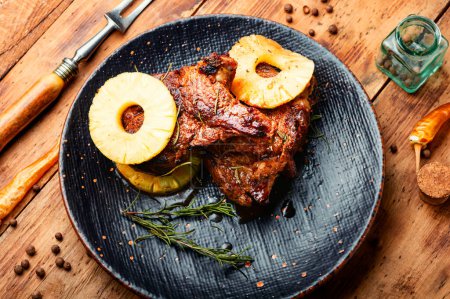 Téléchargez les photos : Steak de viande ou entrecote sur l'os frit à l'ananas sur assiette et fond rustique en bois. - en image libre de droit