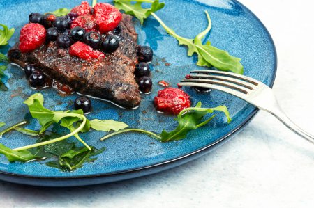 Photo for Fresh juicy beef steak with blueberry and raspberry sauce on the table. - Royalty Free Image