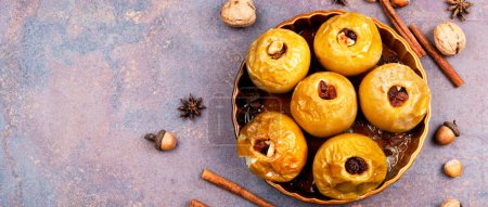 Téléchargez les photos : Pommes sucrées farcies au four avec raisins secs, noix, cannelle dans une assiette. Espace pour le texte, longue bannière. - en image libre de droit