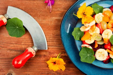 Photo for Salad of fresh fruits and nasturtium leaves on the rustic wooden table. Flat lay. - Royalty Free Image