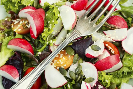 Téléchargez les photos : Salade avec radis, légumes verts, tomate et sésame. Alimentation saine. Gros plan. - en image libre de droit