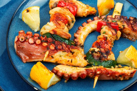 Photo for Tasty seafood octopus tentacles skewers on blue plate. - Royalty Free Image