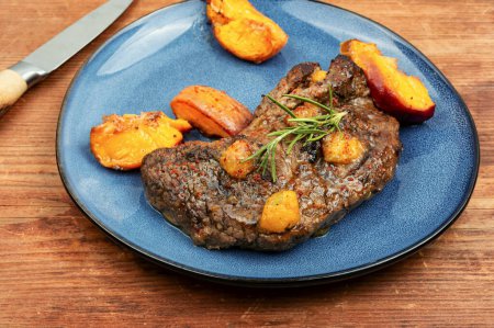 Photo for Diet baked beef steak with peach on wooden table. American cuisine. - Royalty Free Image