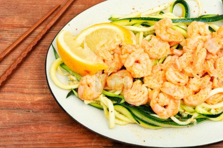 Photo for Appetizing cooked shrimps baked prawns on a vegetable side of zucchini on white plate. - Royalty Free Image