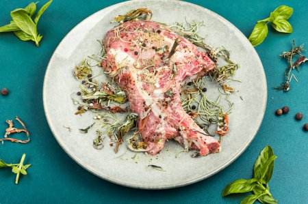 Photo for Raw uncooked steak Tomahawk marinated with spicy herbs for grilling.Raw pork bone steaks. - Royalty Free Image