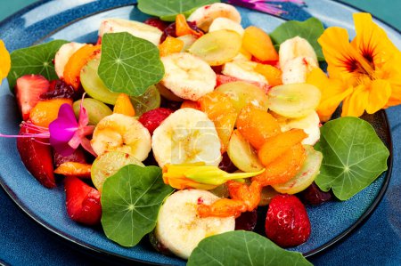 Foto de Ensalada vegetariana de verano de frutas frescas y hojas de capuchina. De cerca.. - Imagen libre de derechos