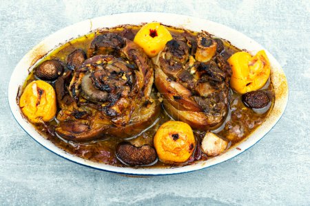 Photo for Roasted pork knuckle eisbein or knee cooked in dark beer and apples in roast pan. Top view. - Royalty Free Image