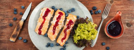 Téléchargez les photos : Poisson de saumon cuit au four avec sauce myrtille. Filets de saumon, steaks grillés sur une table en bois. Vue du dessus. - en image libre de droit