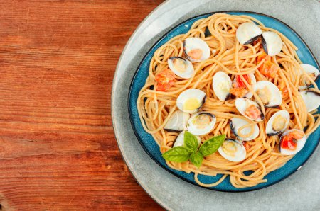 Téléchargez les photos : Pâtes aux fruits de mer avec palourdes ouvertes et spaghettis sur une vieille table rurale en bois. Espace de copie - en image libre de droit