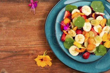 Foto de Ensalada de frutas con vitaminas, plátano, fresas, uvas y capuchina. Espacio para texto. - Imagen libre de derechos