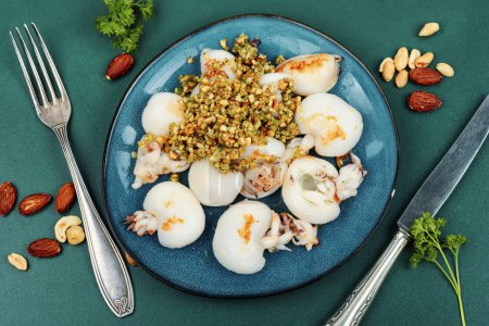 Photo for Baked young squids or calamari with nut garnish. - Royalty Free Image