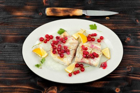 Photo for Cod fillet without skin baked with red currants. Atlantic cod fish on wooden table. - Royalty Free Image