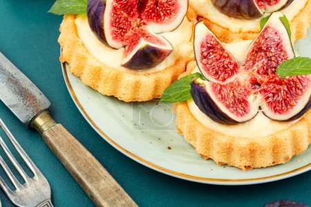 Téléchargez les photos : Tartelettes avec figues et crème anglaise sur une assiette. Tartelettes sucrées aux baies fraîches. Dessert d'automne. - en image libre de droit