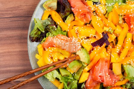 Téléchargez les photos : Salade savoureuse au saumon, mangue, sésame, avocat et poivre. - en image libre de droit