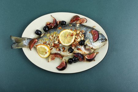 Téléchargez les photos : Dorado rôti aux amandes et figues sur une assiette blanche. Recette d'automne. - en image libre de droit