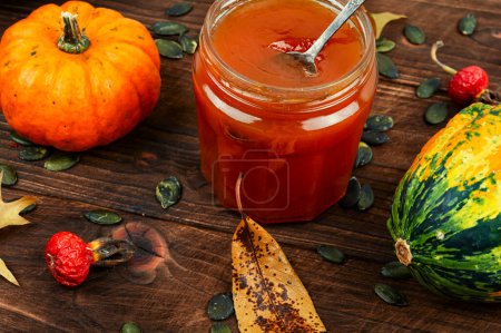 Photo for Pumpkin jam or puree in a glass jar and fresh pumpkins on old wooden table. Autumn still life. - Royalty Free Image
