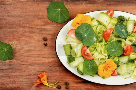 Photo for Rural salad with vegetables, nasturtium and dressing on wooden table. - Royalty Free Image