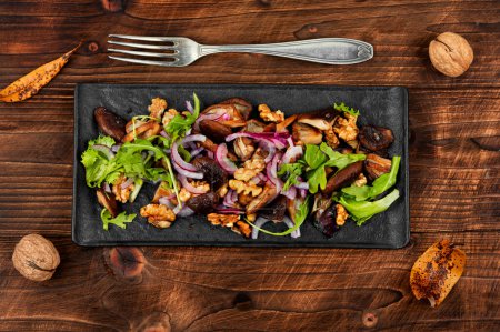 Téléchargez les photos : Salade aux champignons cuits, oignons, herbes et noix sur table en bois noir. Nourriture végétarienne saine. Pose plate. - en image libre de droit