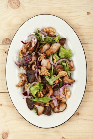 Téléchargez les photos : Salade délicieuse aux champignons de forêt grillés, oignons, herbes et noix. - en image libre de droit