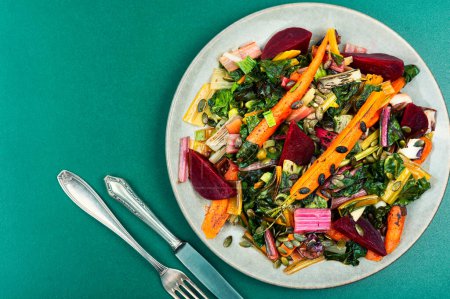 Photo for Salad of stewed chard, beetroot and carrots on a concrete kitchen table . Healthy sauteed swiss chard with vegetables. - Royalty Free Image