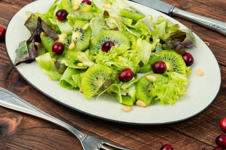 Photo for Fresh salad of kiwi, leafy greens, berries and pine nuts on the table. Clean eating. - Royalty Free Image