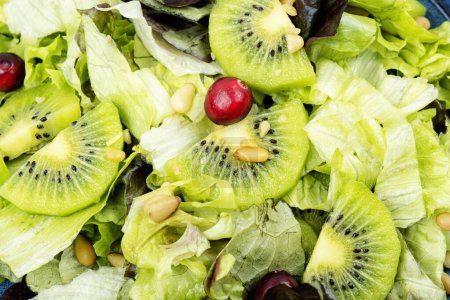 Photo for Fresh vegan salad of kiwi, greens, berries and pine nuts. Clean eating. Close up. - Royalty Free Image