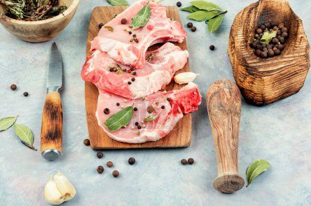 Photo for Raw pork steak in spices on a wooden board. - Royalty Free Image