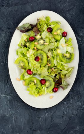 Photo for Delicious fresh salad of kiwi, leafy greens, berries and pine nuts. Top view. - Royalty Free Image
