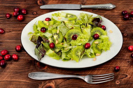 Photo for Vitamin salad of kiwi, greens, berries and pine nuts on wooden table. Clean eating. - Royalty Free Image