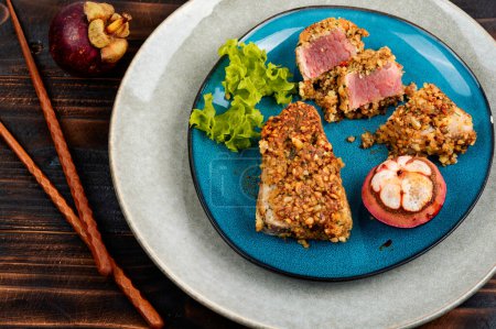 Photo for Delicious steak of baked tuna in a nut with a mangosteens on dark wooden table. - Royalty Free Image
