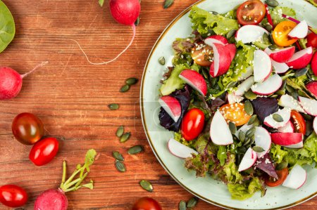 Photo for Vegetarian vegetable salad with radish, greens, tomato and sesame seeds on rustic wooden table. - Royalty Free Image