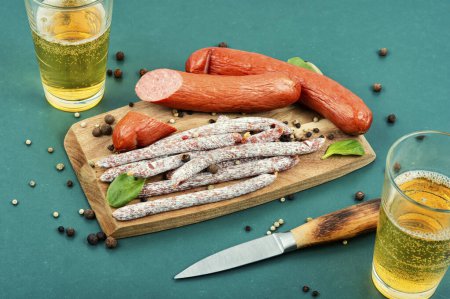 Photo for Smoked kabanos sausages and glass of beer on cutting board. Oktoberfest food. - Royalty Free Image