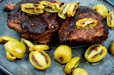 Téléchargez les photos : Steak d'autruche rôti et mini kiwi dans une assiette - en image libre de droit