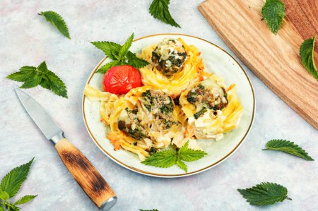 Appetizing nests of noodles with meatballs and nettles. Casserole.