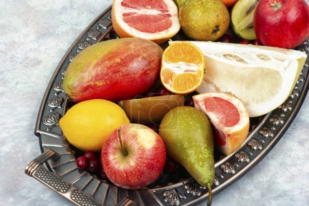 Photo for Apples, pears, mangoes and citrus fruits on a stylish tray. - Royalty Free Image
