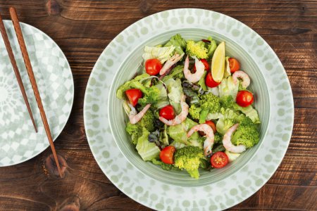 Photo for Asian broccoli salad with shrimp, tomatoes cherry and greens on rustic wooden background. - Royalty Free Image