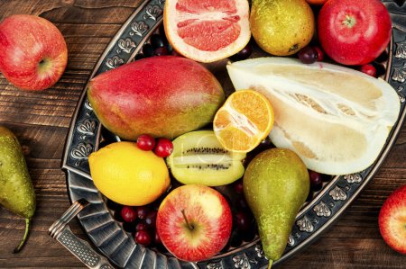 Foto de Manzanas, peras, mangos y cítricos en una bandeja elegante. - Imagen libre de derechos