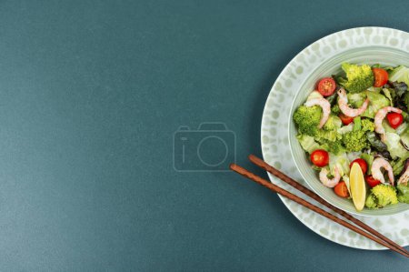 Téléchargez les photos : Salade de brocoli santé aux crevettes, tomates et légumes verts. Pose plate avec espace de copie. - en image libre de droit