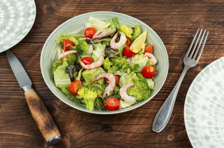 Foto de Ensalada fresca con brócoli, camarones y lechuga. Almuerzo a dieta sobre fondo de madera viejo. - Imagen libre de derechos