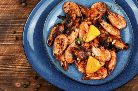 Photo for Fried unpeeled shrimp on a plate. Roast prawns shrimps. Dark rustic wooden background. - Royalty Free Image