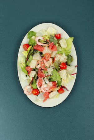 Photo for Pomelo salad with shrimp, tomatoes and lettuce on white plate. Vertical photo. - Royalty Free Image