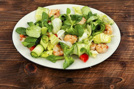 Foto de Plato con ensalada fresca de verduras, hierbas y camarones o gambas. Ensalada de gambas sobre mesa de madera - Imagen libre de derechos
