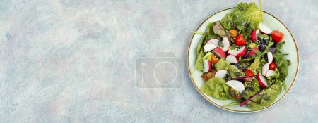 Téléchargez les photos : Salade diététique avec radis, légumes verts, tomates et sésame sur fond gris. Espace pour le texte, - en image libre de droit