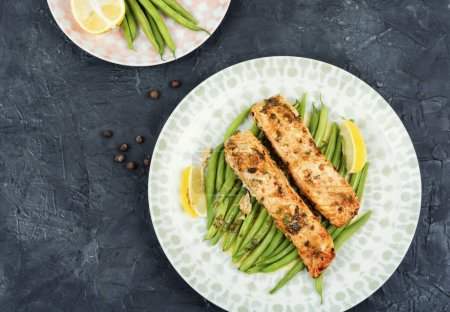 Téléchargez les photos : Filets de saumon cuits au four salés garnis de haricots verts sur une table de cuisine en béton. Vue du dessus. - en image libre de droit