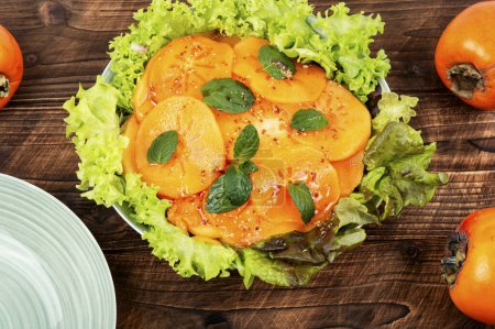 Téléchargez les photos : Salade de désintoxication aux feuilles de laitue, kaki frais et menthe sur table rustique en bois. - en image libre de droit