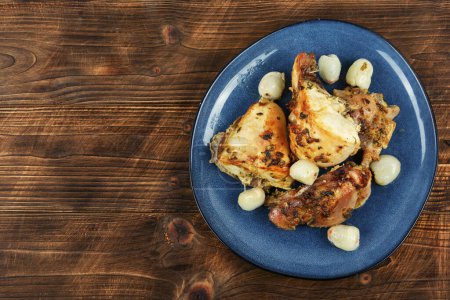 Téléchargez les photos : Des morceaux de poulet rôti avec du litchi dans une assiette. Fond en bois rustique. Espace de copie. - en image libre de droit
