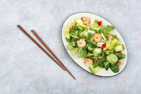 Téléchargez les photos : Assiette avec salade de légumes frais, légumes verts mélangés et crevettes. Salade de crevettes. Nourriture propre, vue du dessus, espace de copie. - en image libre de droit