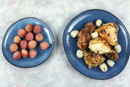 Photo for Pieces of grilled or smoked chicken thighs with lychee on a plate. Top view - Royalty Free Image