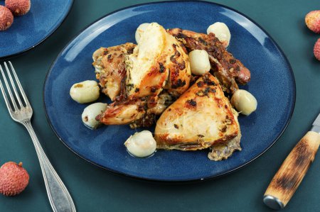 Téléchargez les photos : Des morceaux de poulet rôti avec du litchi dans une assiette. Volailles grillées. - en image libre de droit